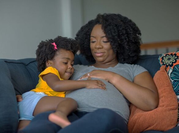 Een zwangere moeder die haar buik streelt met haar dochter.
