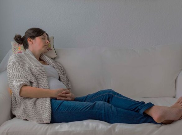 Zwangere moeder dut op een bank.