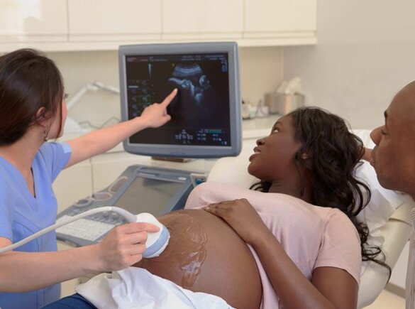 Een zwangere vrouw wordt onderzocht met een echografie terwijl de vader naast haar zit.