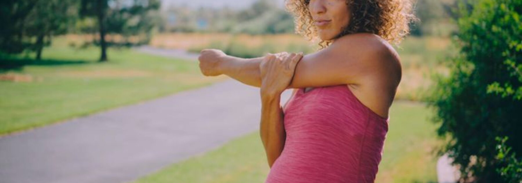 Een zwangere moeder die zich buiten uitrekt.
