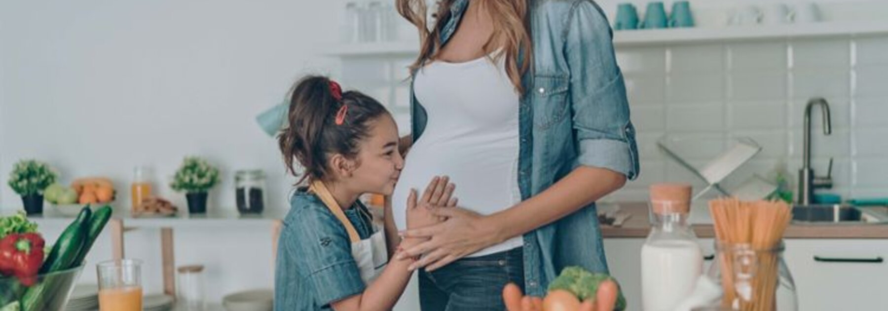 Een zwangere moedersdochter die haar buik kust.