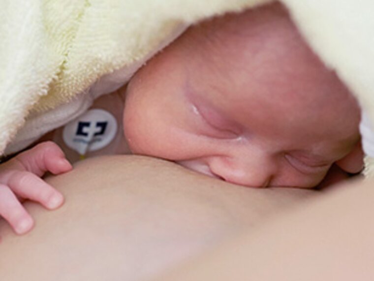 Newborn baby initiating breastfeeding with mother in hospital