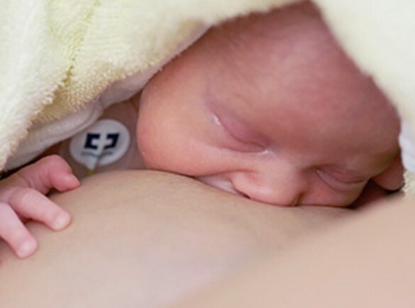 Neugeborenes Baby, das mit der Mutter im Krankenhaus zu stillen beginnt