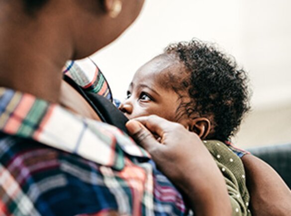 A mom breastfeeding her baby while it faces her.