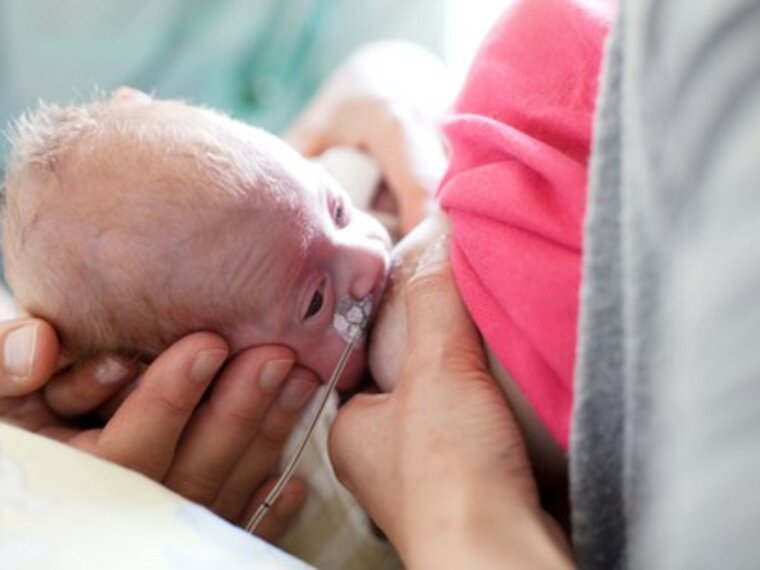 A mother breastfeeds her premature baby.