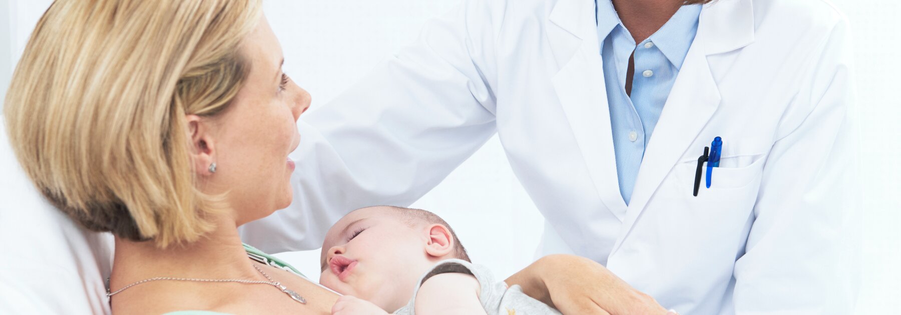 Un bébé dort sur la poitrine de sa mère pendant qu'elle parle à un professionnel de la santé. 