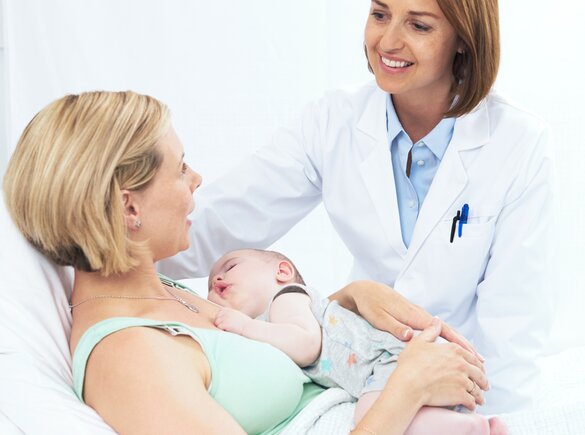 Un bébé dort sur la poitrine de sa mère pendant qu'elle parle à un professionnel de la santé. 