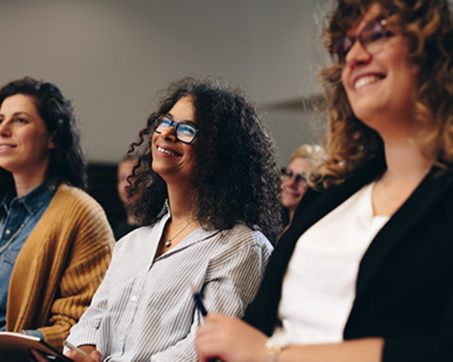 A smiling audience listening to someone speak.