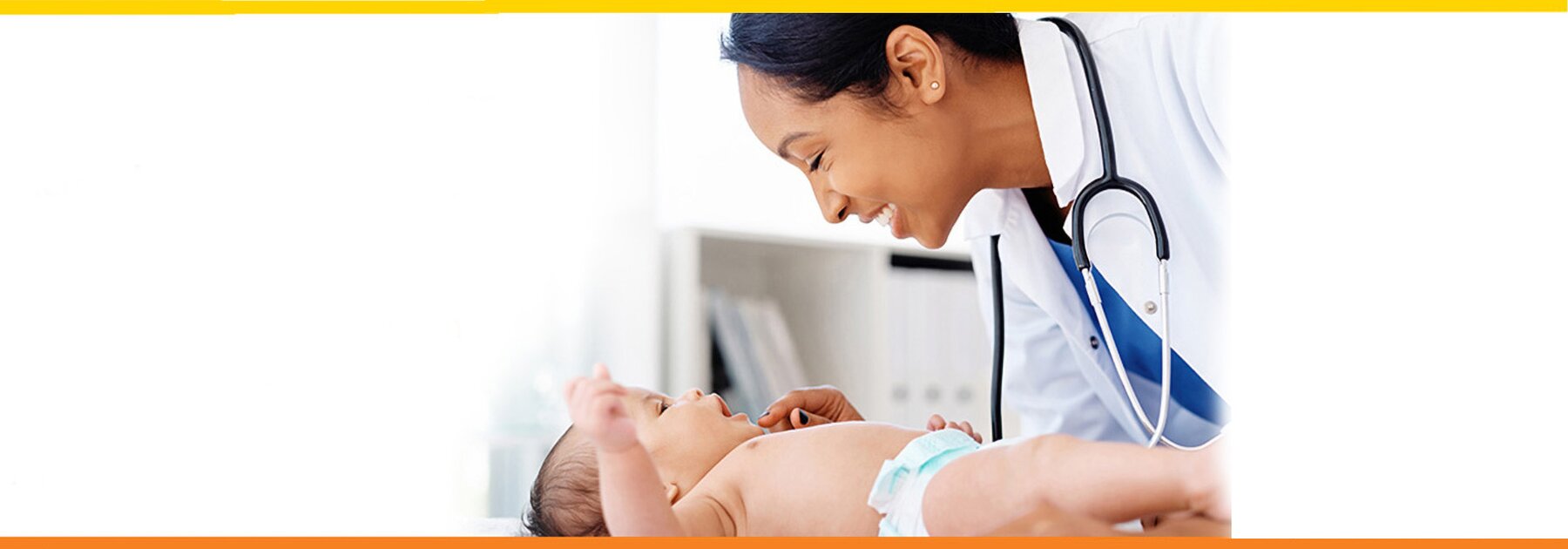 Baby on an exam table, medical professional leaning over baby smiling.