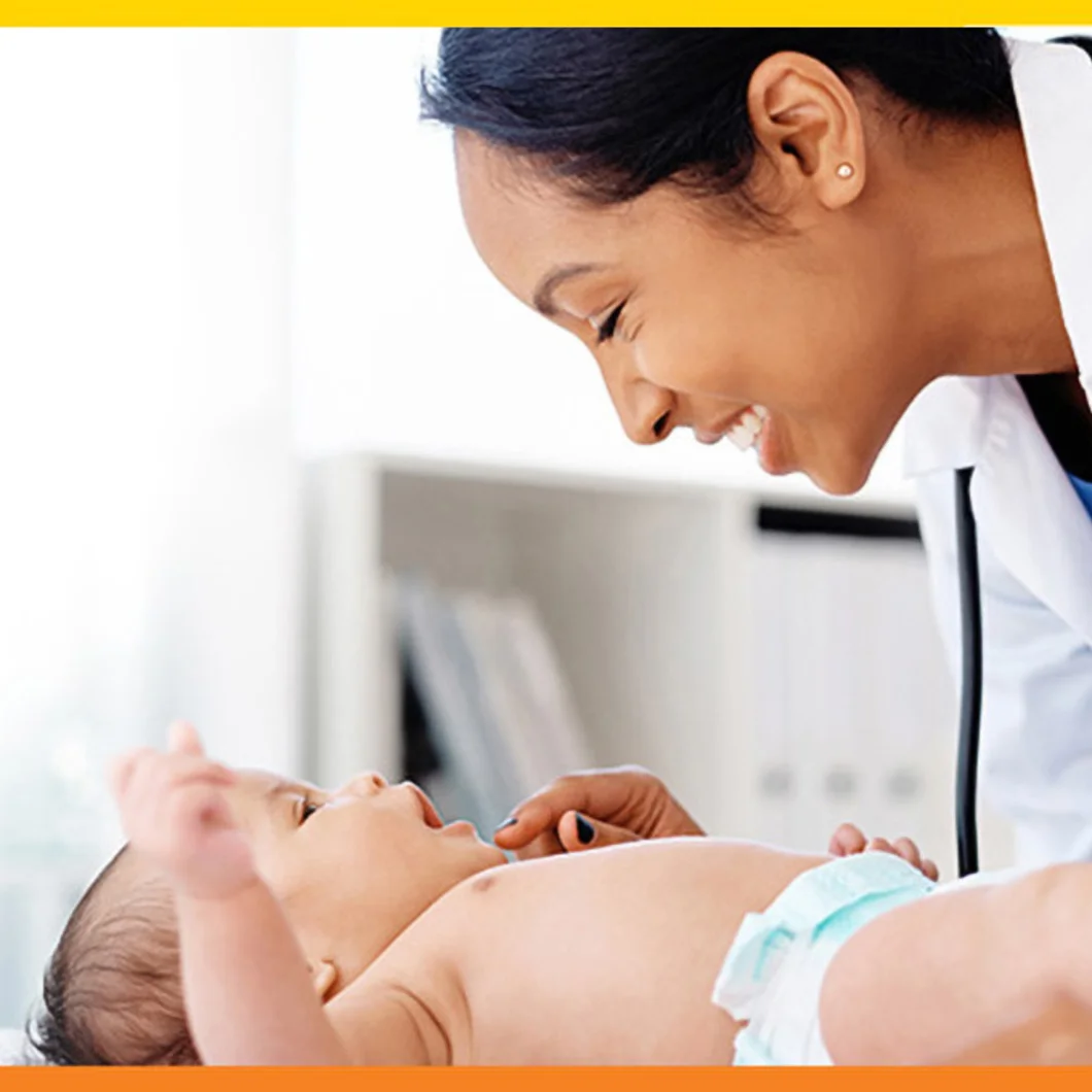 Baby on an exam table, medical professional leaning over baby smiling.