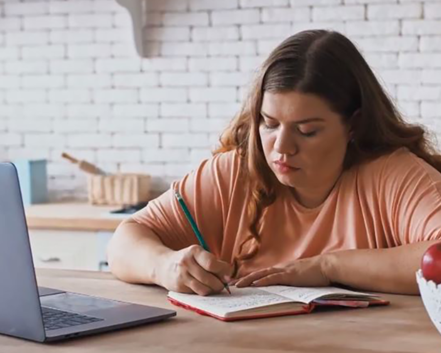 Vrouw maakt aantekeningen voor een laptop