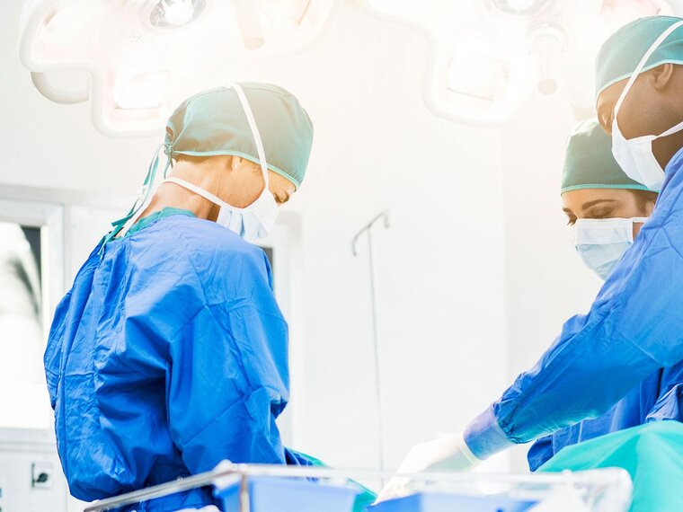 Médecins dans une salle d'opération avec un patient. La salle est visible du centre au plafond, le patient lui-même n'est pas représenté.