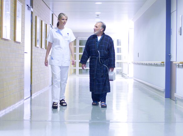 Un médecin et un patient marchent dans un couloir d'hôpital.