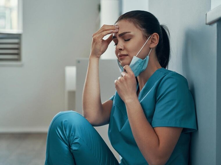 Medizinisches Fachpersonal sitzt auf dem Boden und sieht müde oder verzweifelt aus