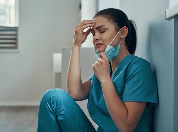 Medizinisches Fachpersonal sitzt auf dem Boden und sieht müde oder verzweifelt aus