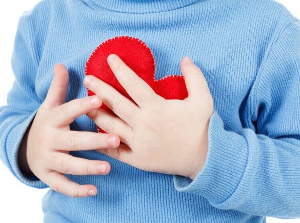 Ein Kind, das sich einer Kinderherzoperation unterziehen muss, hält ein Herz aus Stoff in der Hand.