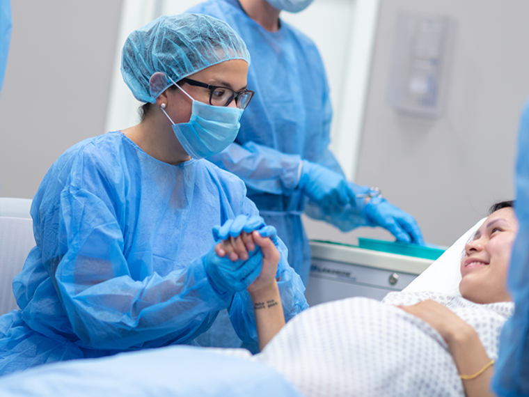 Operating room with doctor holding pregnant mother's hand