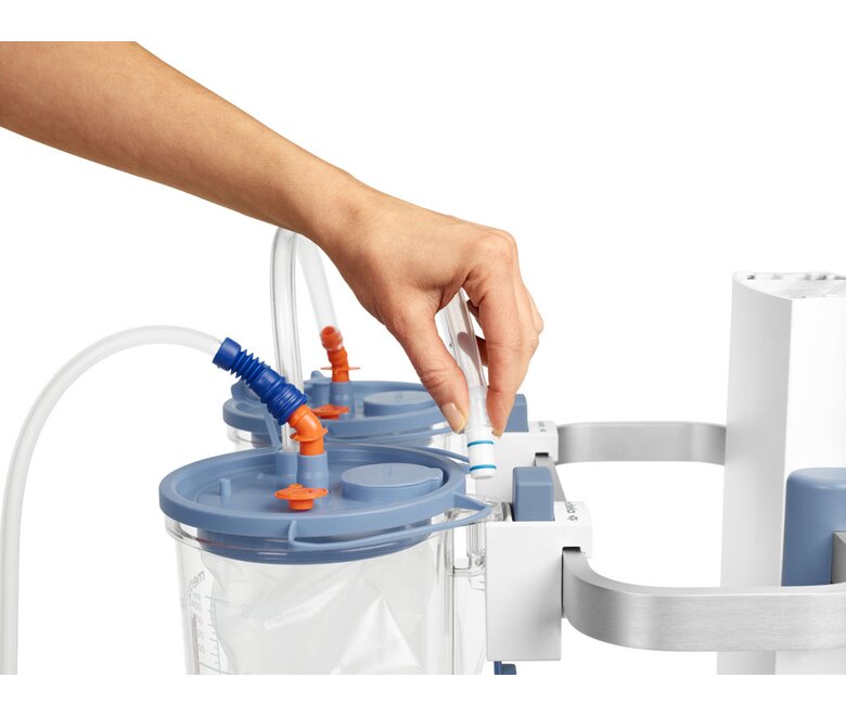 Hand placing vacuum suction tubing on top of Medela canister.