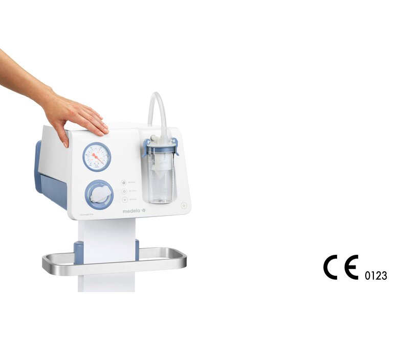 De hand van een persoon rust op de Medela Dominant Flex chirurgische afzuigpomp boven de vacuümmeter.
