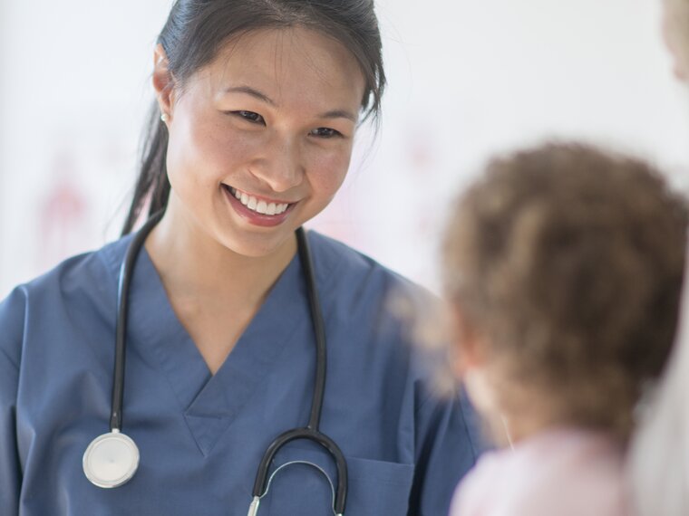 Krankenschwester lächelt einer Frau zu, die ein Baby hält