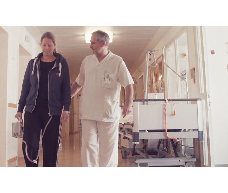 Eine medizinische Fachkraft geht mit einem Patienten, der das tragbare digitale Thoraxdrainage- und Überwachungssystem Thopaz+ trägt.