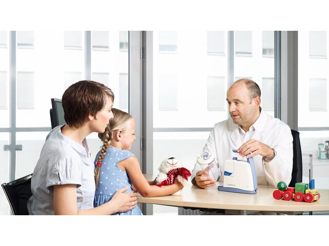 Doctor showing mother and daughter a Medela airway suction Clario Toni pump.