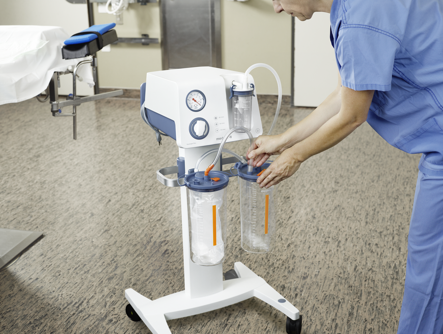 A healthcare provider sets up a Medela Dominant Flex surgical suction pump in a hospital.