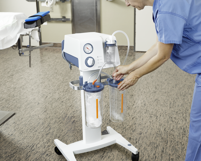 A healthcare provider sets up a Medela Dominant Flex surgical suction pump in a hospital.