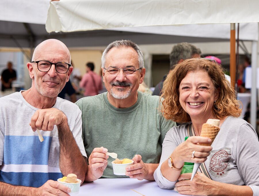 Two men and a woman enjoying ice cream together.