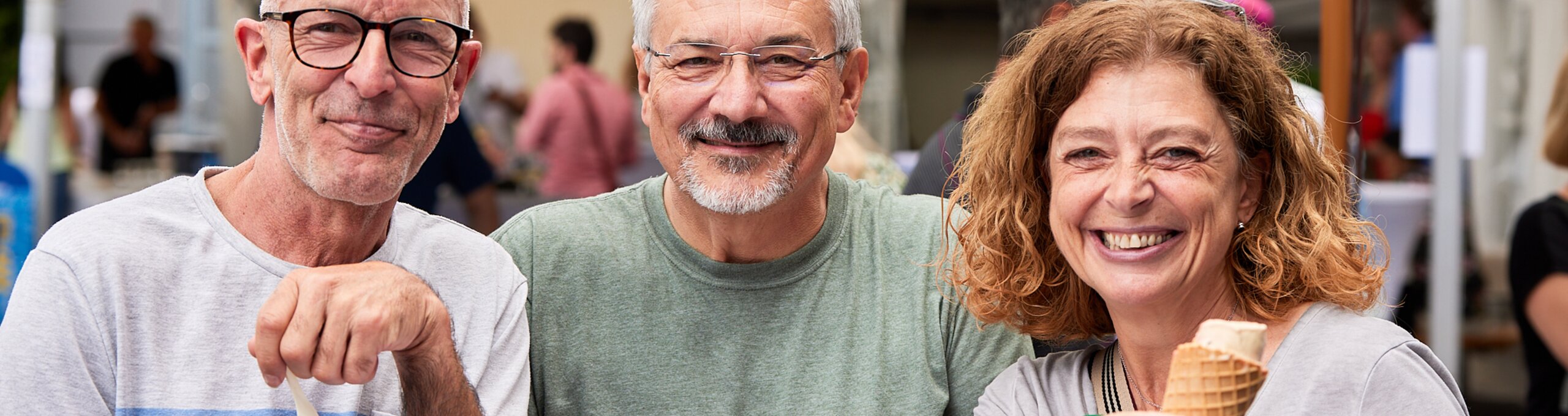 Zwei Männer und eine Frau, die zusammen ein Eis genießen.