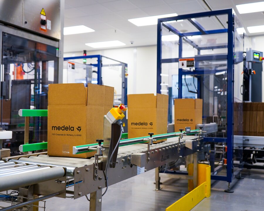 Warehouse conveyor belt system with Medela boxes moving along them.