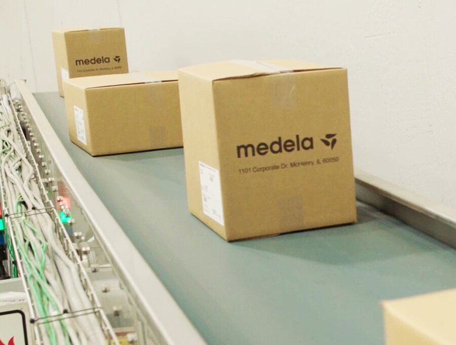 Boxes labeled "Medela" on a conveyor belt.