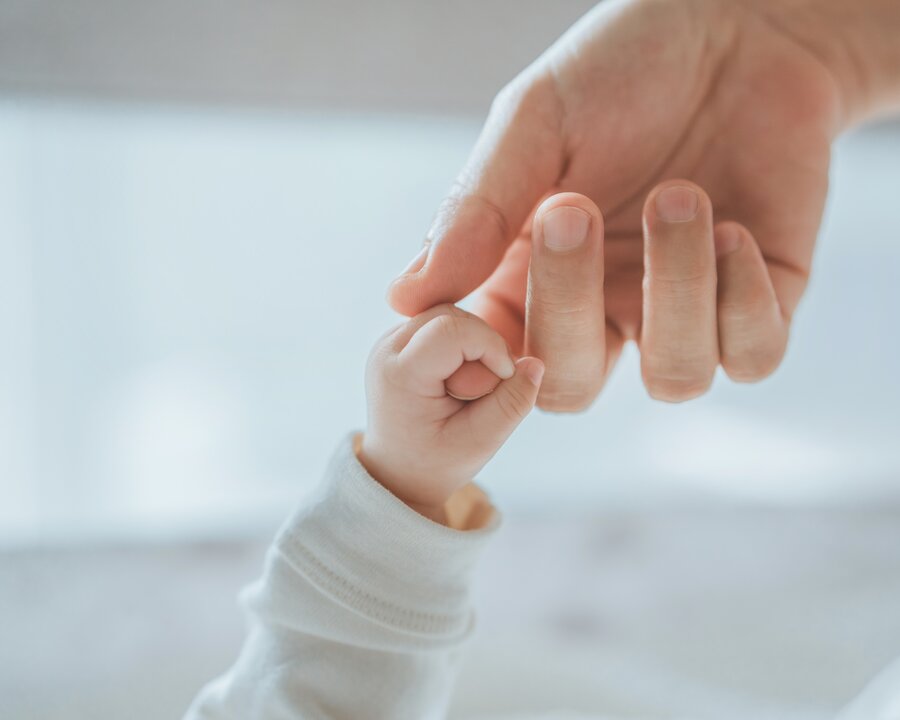 Zwei Stillberaterinnen blicken auf eine Mutter, die ihr neugeborenes Baby im Arm hält.