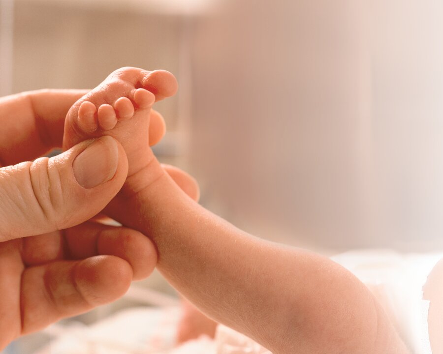 Hand holding the foot of a newborn baby.