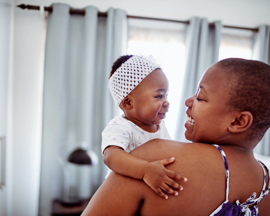 Mom holding her infant and them smiling at one another.