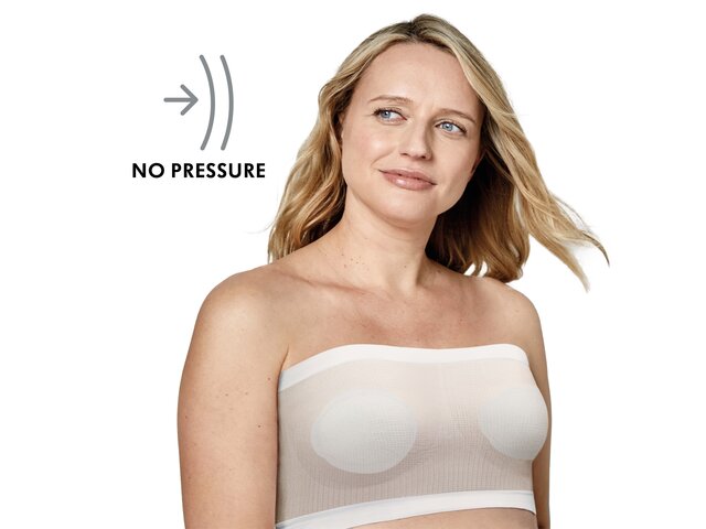 A woman wears the Medela No Pressure Band™ bra in white, front view. Text: “No pressure”