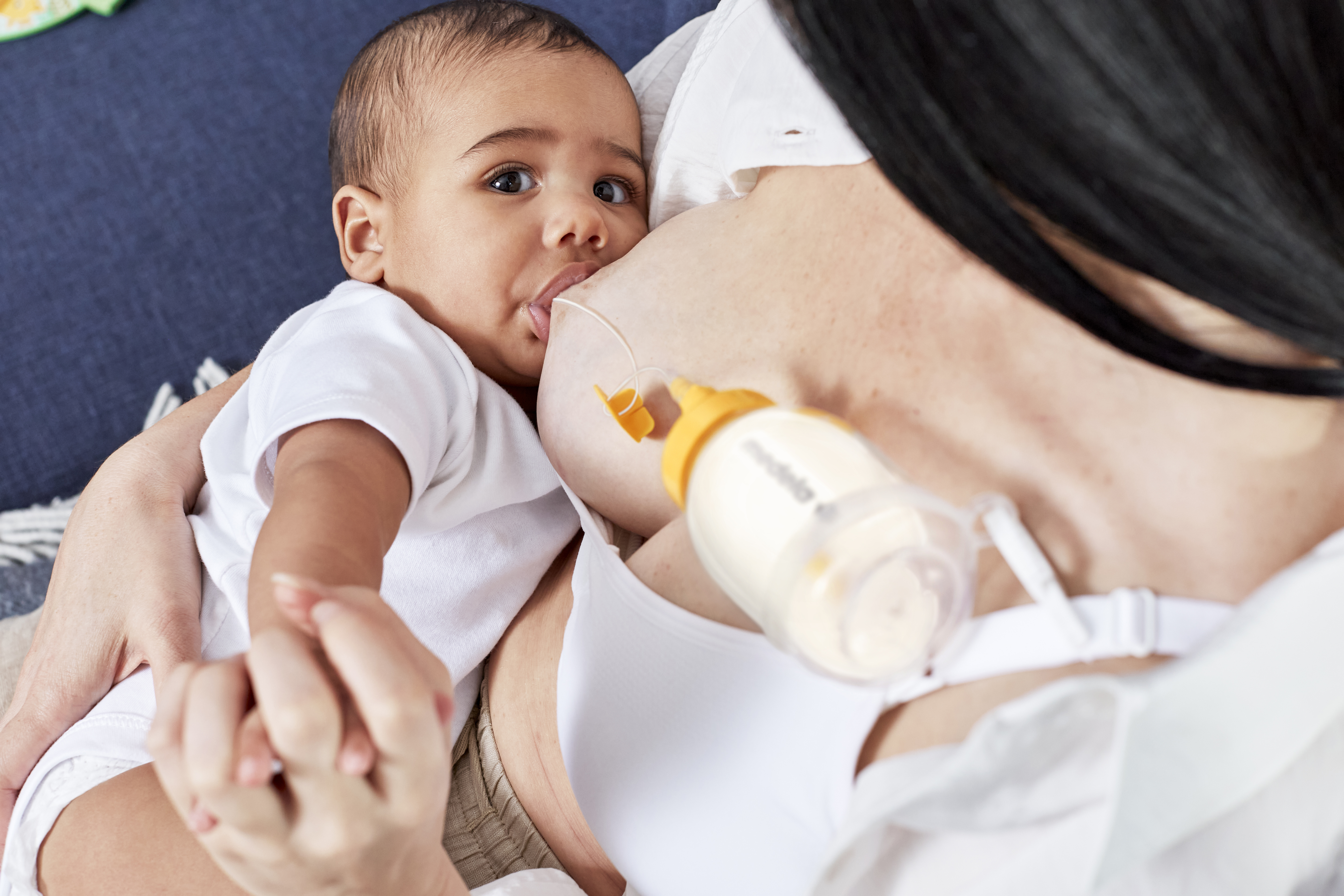 A mom breastfeeding her baby and supplementing the diet using Medela's Supplemental Nursing System™ (SNS).