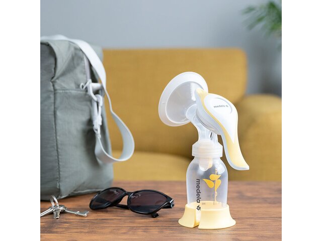 De Medela Harmony™ handmatige borstkolf thuis op tafel, klaar om mee te nemen met sleutels, bril en luiertas.