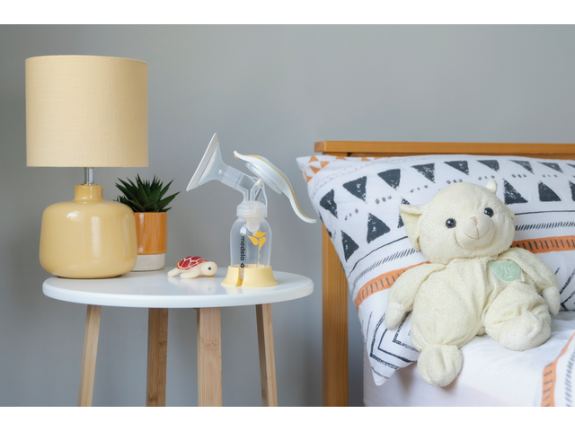 Medela Harmony borstkolf op tafel naast het bed in een kinderkamer.