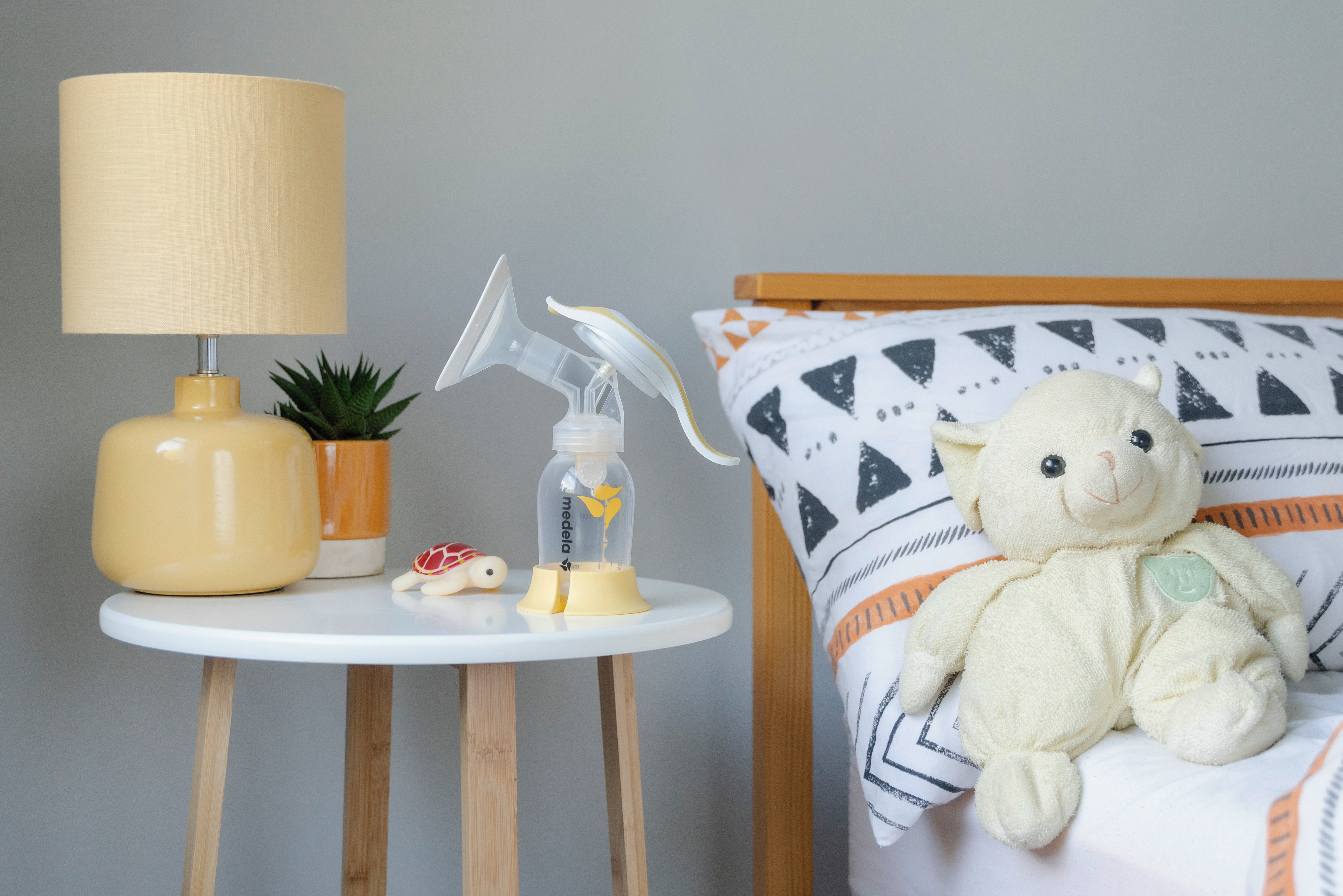 Medela Harmony breast pump sitting on table next to bed in a nursery.