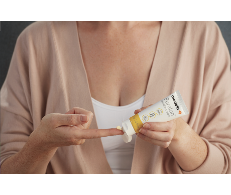 A mom measures a droplet of Medela Purelan™ Lanolin Cream on her finger.