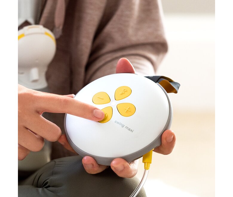 Frau drückt den Knopf ihrer elektrischen Medela Swing Maxi™ Doppelmilchpumpe