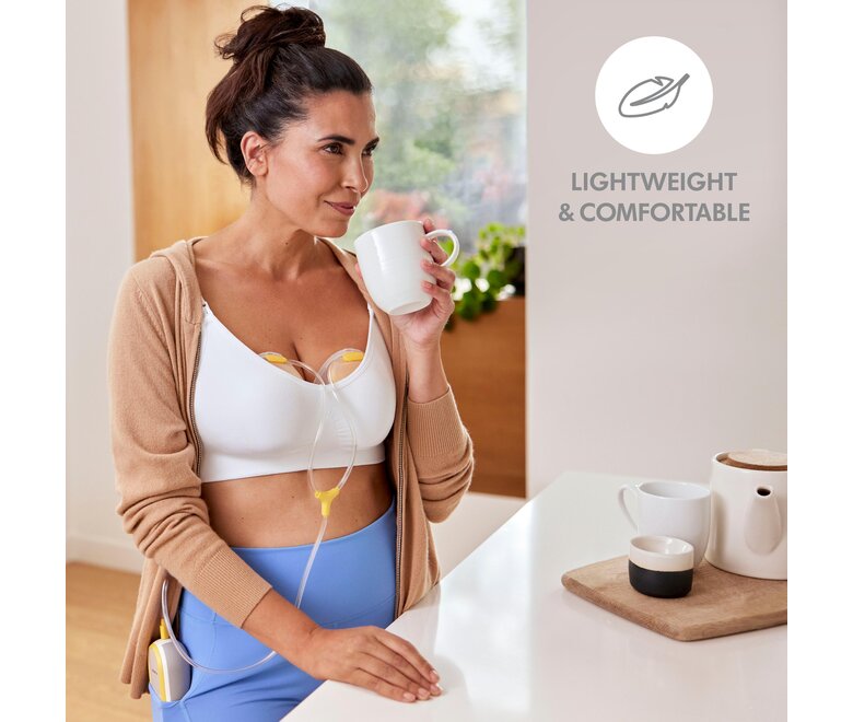 Mama drinkt koffie terwijl ze haar Medela Freestyle™ Hands-free dubbele elektrische draagbare borstkolf draagt. De tekst op de afbeelding zegt: “Lichtgewicht en comfortabel.