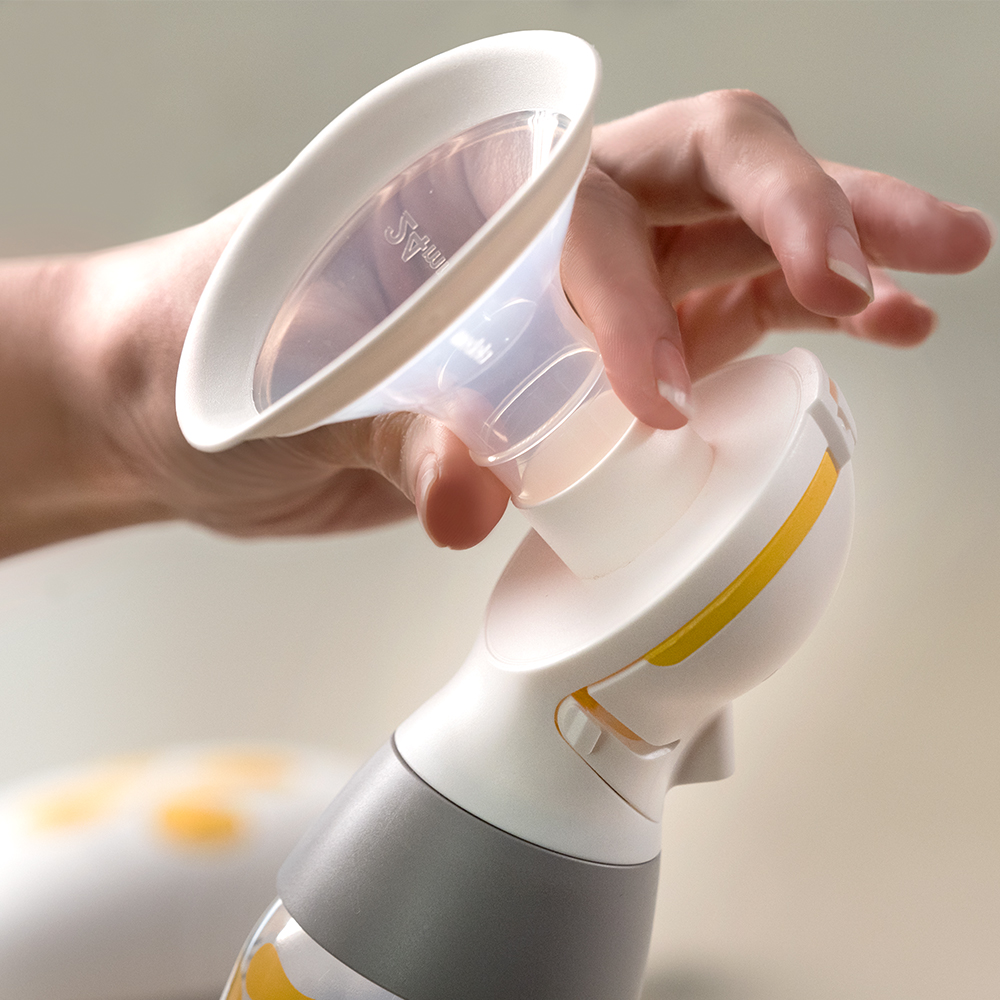 A person's hands demonstrate how to attach and remove the Medela PersonalFit Flex™ breast shield.