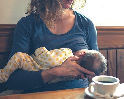 A mother breastfeeds her baby in public.