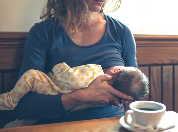 A mother breastfeeds her baby in public.