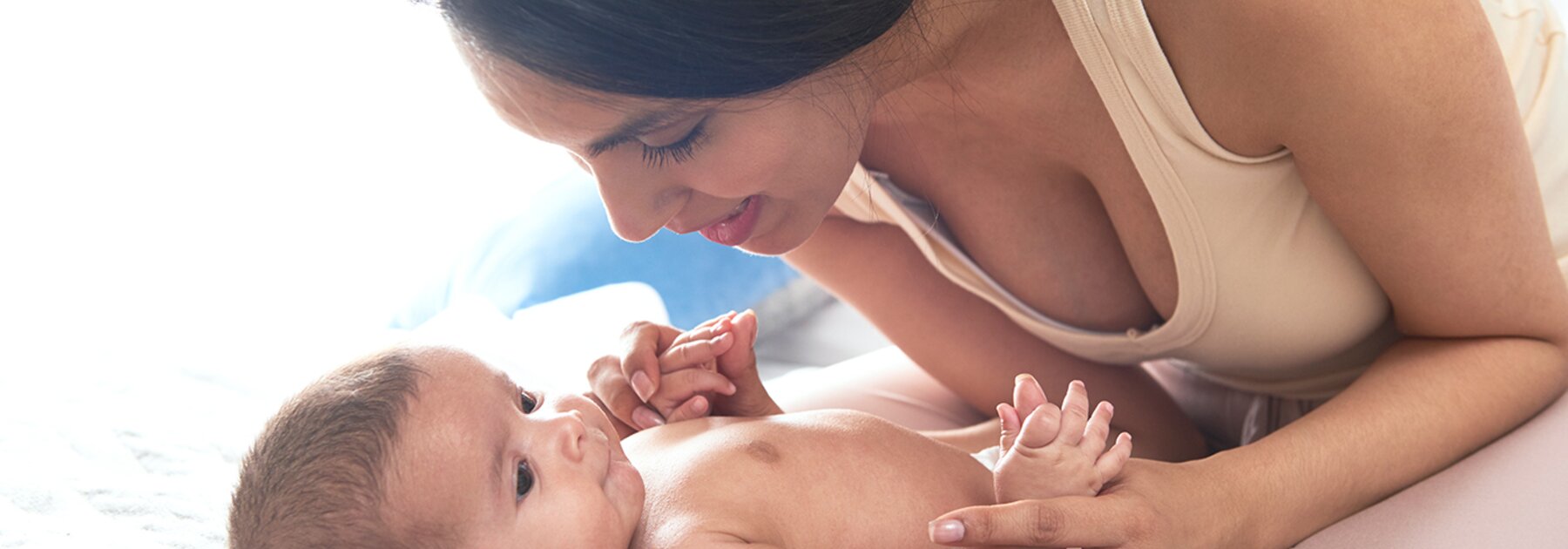 Una madre juega con su bebé en la cama.