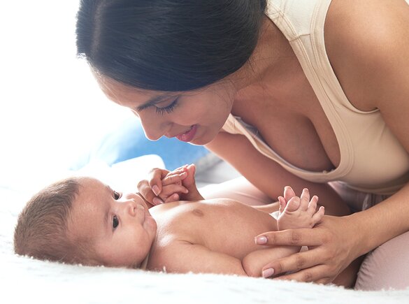 Una madre juega con su bebé en la cama.