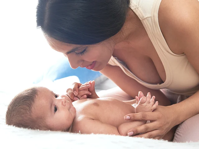 Une mère joue avec son bébé sur le lit.