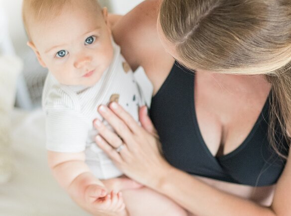 Um bebé olha para a câmara acima enquanto é segurado pela mãe.